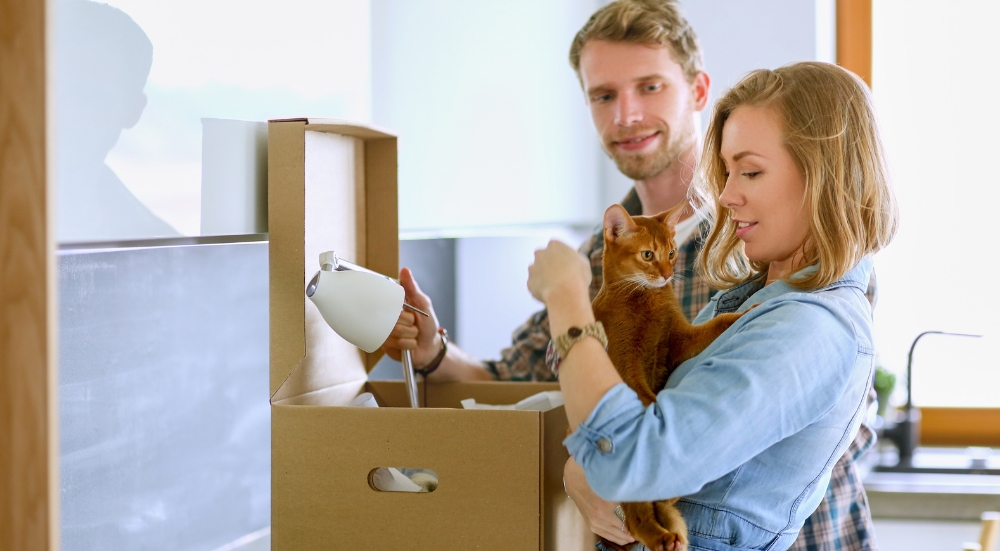 Un jeune couple prépare ses cartons pour un déménagement avec un chat au Luxembourg.